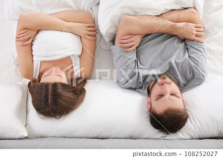 Upset young woman near sleeping husband in bed, top view. Relationship problems Upset young woman near sleeping husband in bed, top view. Relationship problems 108252027