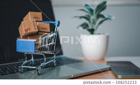 Shopping cart and product boxes placed on laptop computer represent online shopping concept, website, e-commerce, marketplace platform, technology, transportation, logistics and online payment Shopping cart and product boxes placed on laptop computer represent online shopping concept, website, e-commerce, marketplace platform, technology, transportation, logistics and online payment 108252213