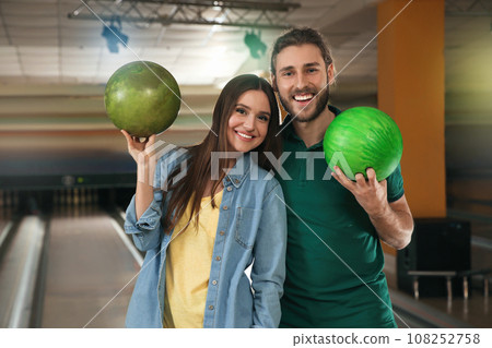 Happy young couple with balls in bowling club Happy young couple with balls in bowling club 108252758