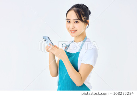 穿著圍裙的年輕家庭主婦使用計算機 穿著圍裙的年輕家庭主婦使用計算機 108253284