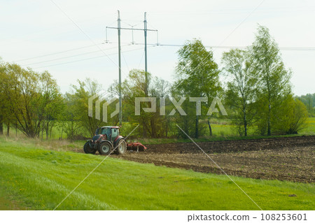 A tractor with plows cultivates the land. A tractor with plows cultivates the land. 108253601