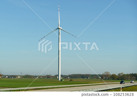 Wind turbine of a wind power plant standing along the road, against the background of a blue sky. Wind turbine of a wind power plant standing along the road, against the background of a blue sky. 108253628