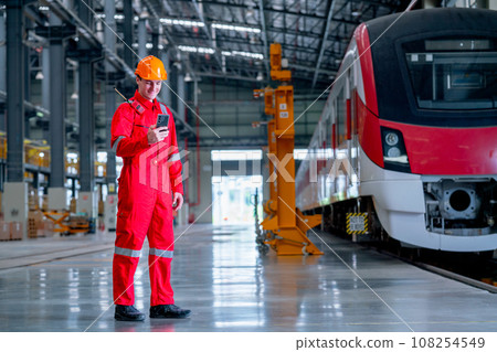Professional technician worker stand near the train and hold and look to mobile phone in factory 108254549