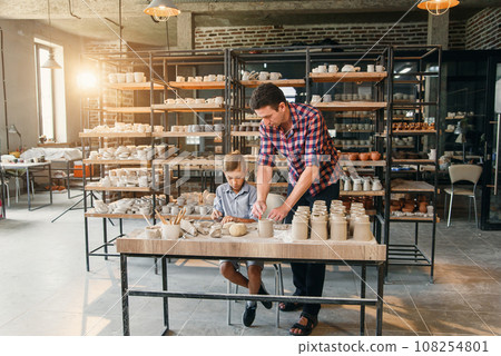 Attractive caucasian man and liitle cute boy kneading clay for pots. Attractive caucasian man and liitle cute boy kneading clay for pots. 108254801