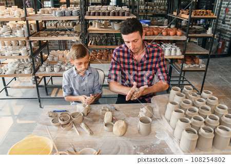 Attractive caucasian man and liitle cute boy kneading clay for pots. Attractive caucasian man and liitle cute boy kneading clay for pots. 108254802