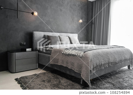 Master bedroom for a lonely stylish man, a bachelor. Modern room with trendy gray interiors, large king-size and lamps. Master bedroom for a lonely stylish man, a bachelor. Modern room with trendy gray interiors, large king-size and lamps. 108254894