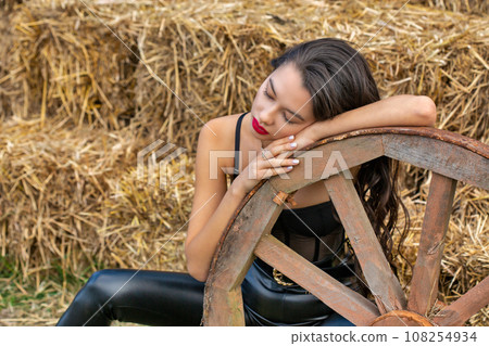 Beautiful young caucasian woman with wooden cart wheel. Beautiful young caucasian woman with wooden cart wheel. 108254934