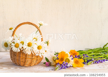 Bouquet of white daisies in the wicker basket on the white paint wooden background; copy space 108254955