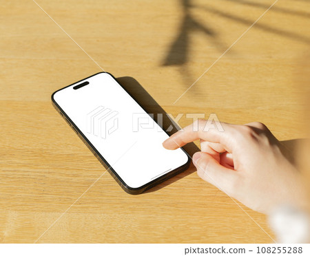 Berlin, Germany October 20 2023 Finger clicking, tapping on mobile phone screen mock up, display mockup on wooden table 108255288