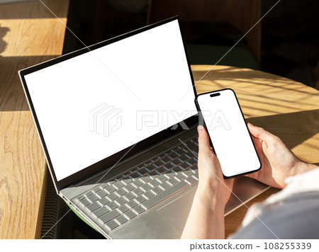 Berlin, Germany October 20 2023 Hands holding smart phone screen mock up, notebook computer 108255339