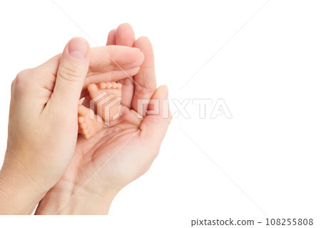 World Prematurity Day on 17th November. Woman hand with a baby feet . Motherhood and care. 108255808