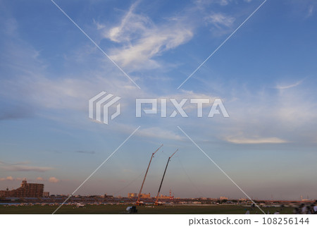 The sky dyed in the sunset, buildings, buildings, riverbed, sunset, people gathering at sunset, sunset sky, silhouettes of people 108256144
