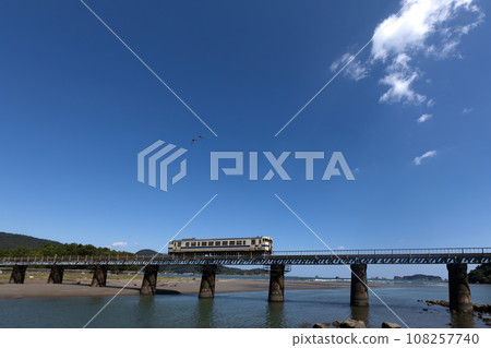 Kiha 40 on the Nichinan Line running on the iron bridge over the Hosoda River under the blue sky 108257740