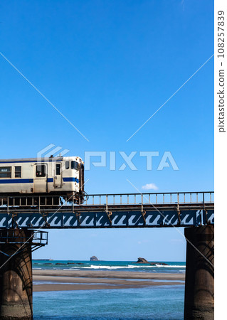 Kiha 40 on the Nichinan Line running on the iron bridge over the Hosoda River under the blue sky 108257839