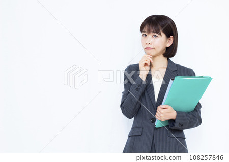 A working woman in her 30s wearing a suit who is worried in front of a white background A working woman in her 30s wearing a suit who is worried in front of a white background 108257846