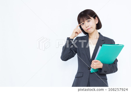 A working woman in her 30s who is in trouble in front of a white background A working woman in her 30s who is in trouble in front of a white background 108257924