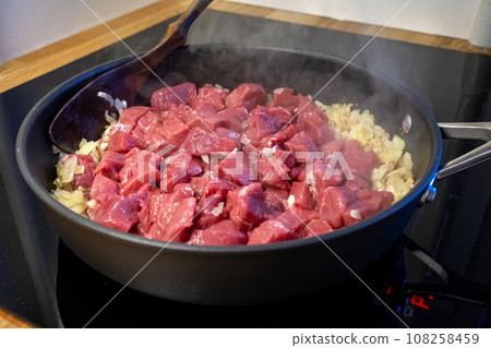 raw meat and chopped onion on cooking pan raw meat and chopped onion on cooking pan 108258459