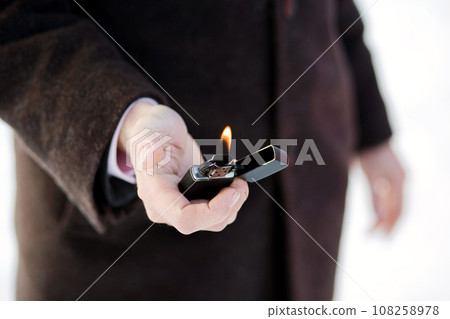 Close-Up of Hand Holding a Lit Lighter 108258978
