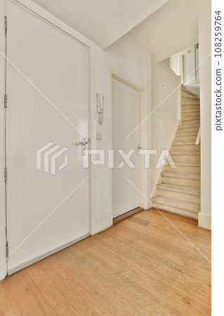 an empty room with white walls and wood flooring on the right side, there is a staircase leading up to the second floor an empty room with white walls and wood flooring on the right side, there is a staircase leading up to the second floor 108259764