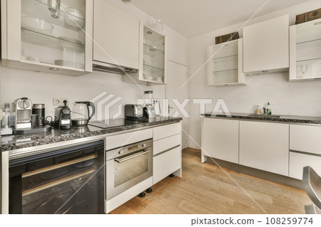 a kitchen with white cupboards and black counter tops on the stove in this photo is taken from the inside a kitchen with white cupboards and black counter tops on the stove in this photo is taken from the inside 108259774