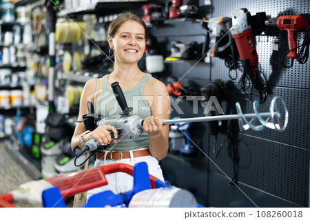 Woman choose examines building mixer in tools department of construction store Woman choose examines building mixer in tools department of construction store 108260018