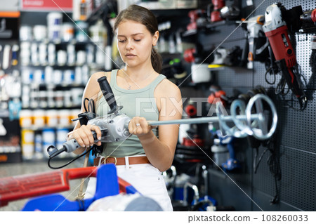 Young female buyer chooses mixer for building mixtures in hardware store 108260033