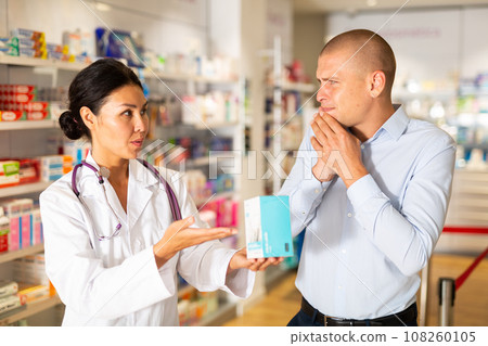 Female pharmacist helping man with toothache in drugstore Female pharmacist helping man with toothache in drugstore 108260105
