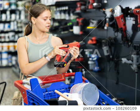 Female customer choosing electric drill in hardware store 108260109