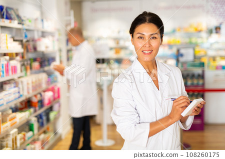 Female pharmacist standing in drugstore 108260175