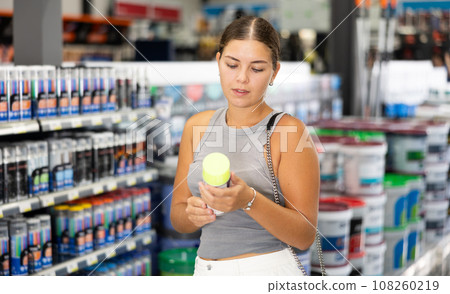 Young woman choose cans of aerosol paint in hardware store 108260219