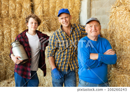 Portrait of farmers of different generations against background of hay bales. Concept of intergenerational continuity Portrait of farmers of different generations against background of hay bales. Concept of intergenerational continuity 108260243