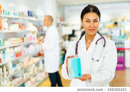 Oriental female pharmacist standing in salesroom of drugstore Oriental female pharmacist standing in salesroom of drugstore 108260261