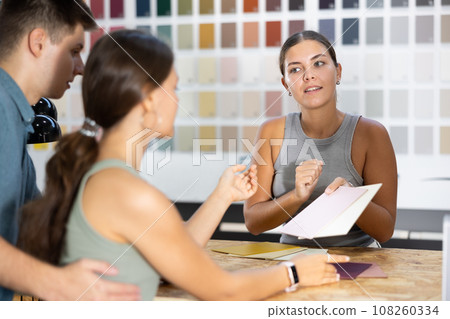 Seller of hardware store advises couple of buyer what ceramic tiles to buy 108260334