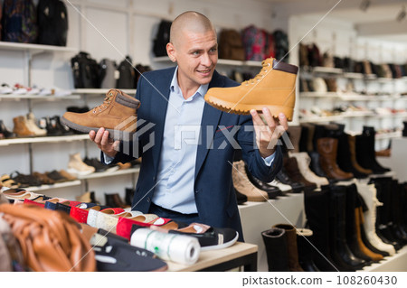 Cheerful man choosing demi-season lace up boots in store Cheerful man choosing demi-season lace up boots in store 108260430