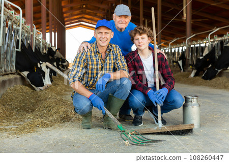 Continuity of generations - portrait of farmers of different ages against the backdrop of cowshed Continuity of generations - portrait of farmers of different ages against the backdrop of cowshed 108260447