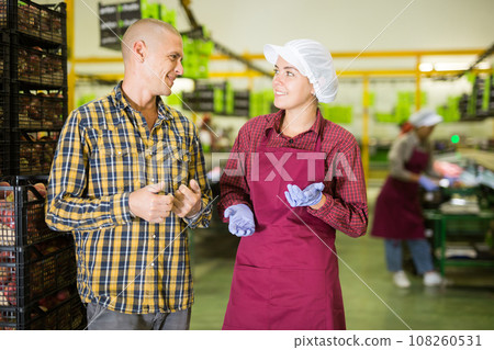 Manager and hired employee communicate during breaks between work in fruit warehouse 108260531