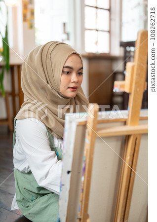 A talented Asian-Muslim female artist is focusing on creating her artwork, painting on canvas. 108262718