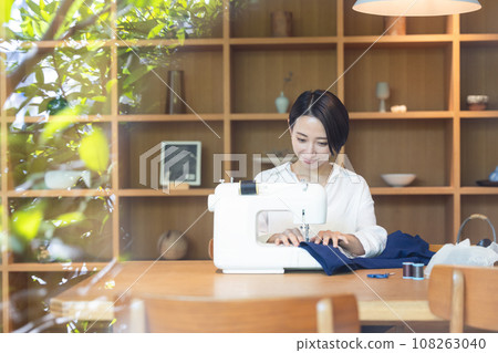 A woman sewing with a sewing machine 108263040