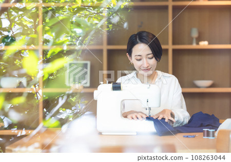 A woman sewing with a sewing machine in the living room A woman sewing with a sewing machine in the living room 108263044