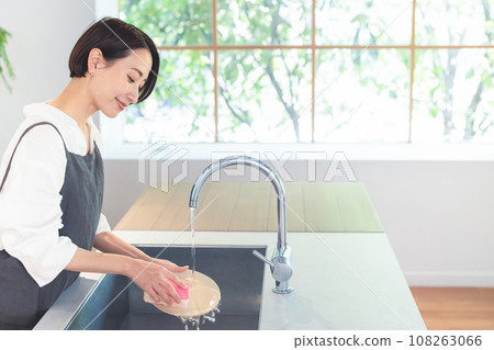 Woman washing dishes in kitchen Woman washing dishes in kitchen 108263066