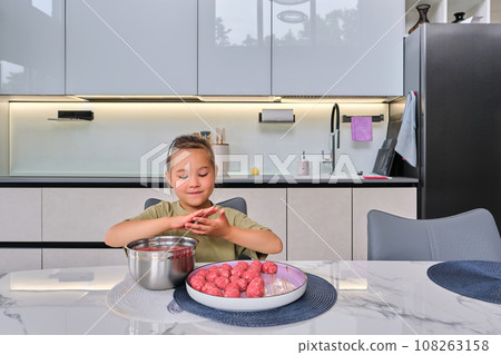 A girl is preparing meatballs in the kitchen. 108263158