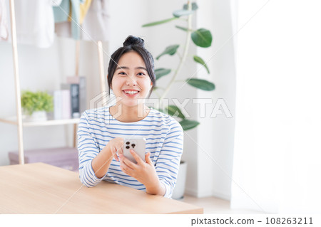 年輕女子在客廳看智慧型手機 年輕女子在客廳看智慧型手機 108263211