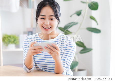 一個年輕的女人,看著她的智能手機上的視頻 一個年輕的女人,看著她的智能手機上的視頻 108263254