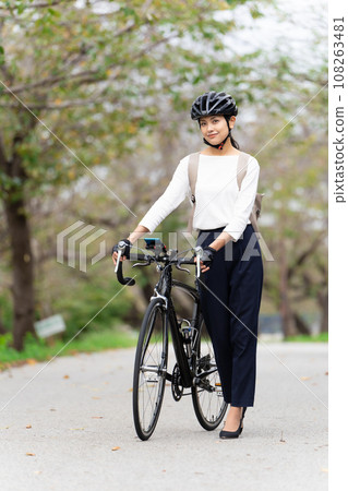 Young woman in business casual clothes walking while pushing a road bike 108263481