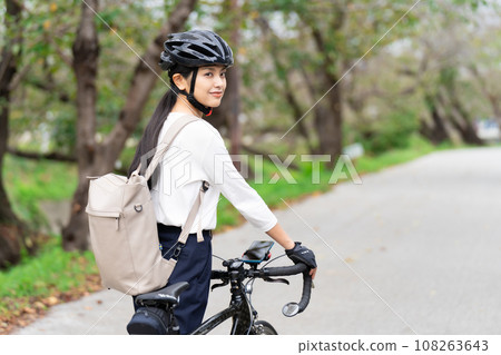 一位年輕女子穿著商務休閒服推著公路自行車行走，後視 108263643