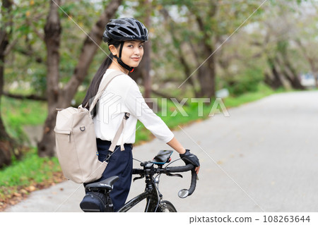 一位年輕女子穿著商務休閒服推著公路自行車行走,後視 一位年輕女子穿著商務休閒服推著公路自行車行走,後視 108263644