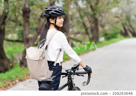 一位年輕女子穿著商務休閒服推著公路自行車行走，後視 108263646