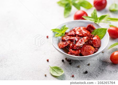 Bowl with sun dried tomatoes with fresh herbs and spices. 108265764