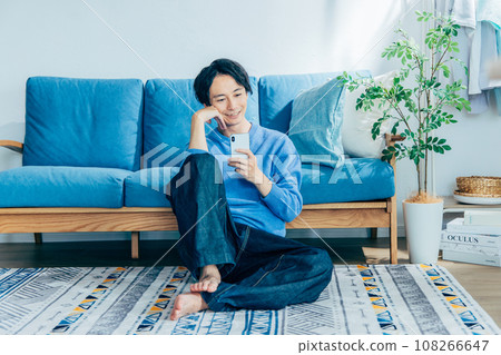 Young man using smartphone in the living room Young man using smartphone in the living room 108266647