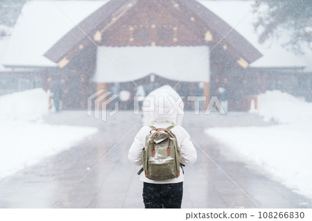 Woman tourist Visiting in Sapporo, Traveler in Sweater looking Hokkaido Shrine with Snow in winter season. landmark and popular for attractions in Hokkaido, Japan. Travel and Vacation concept Woman tourist Visiting in Sapporo, Traveler in Sweater looking Hokkaido Shrine with Snow in winter season. landmark and popular for attractions in Hokkaido, Japan. Travel and Vacation concept 108266830